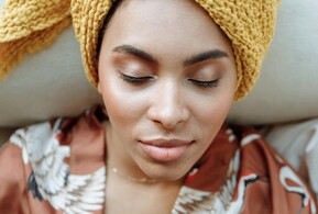 Une femme en surpoids souriante dans une robe jaune. Illustre une formation en naturopathie sur la résistance à l'insuline. 