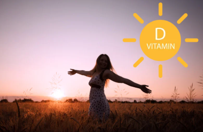 Une femme dansant dans un champ lors d'un coucher de soleil avec un dessin de soleil illustrant la vitamine D